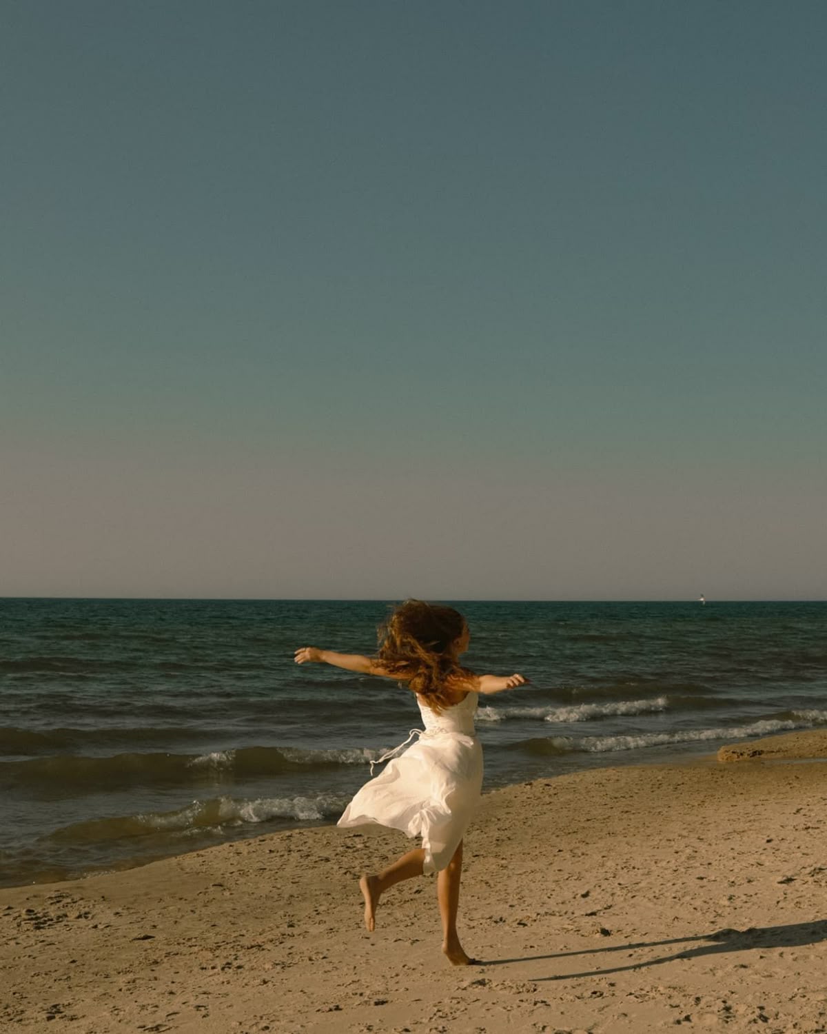 Mujer caminando sola por la playa al atardecer