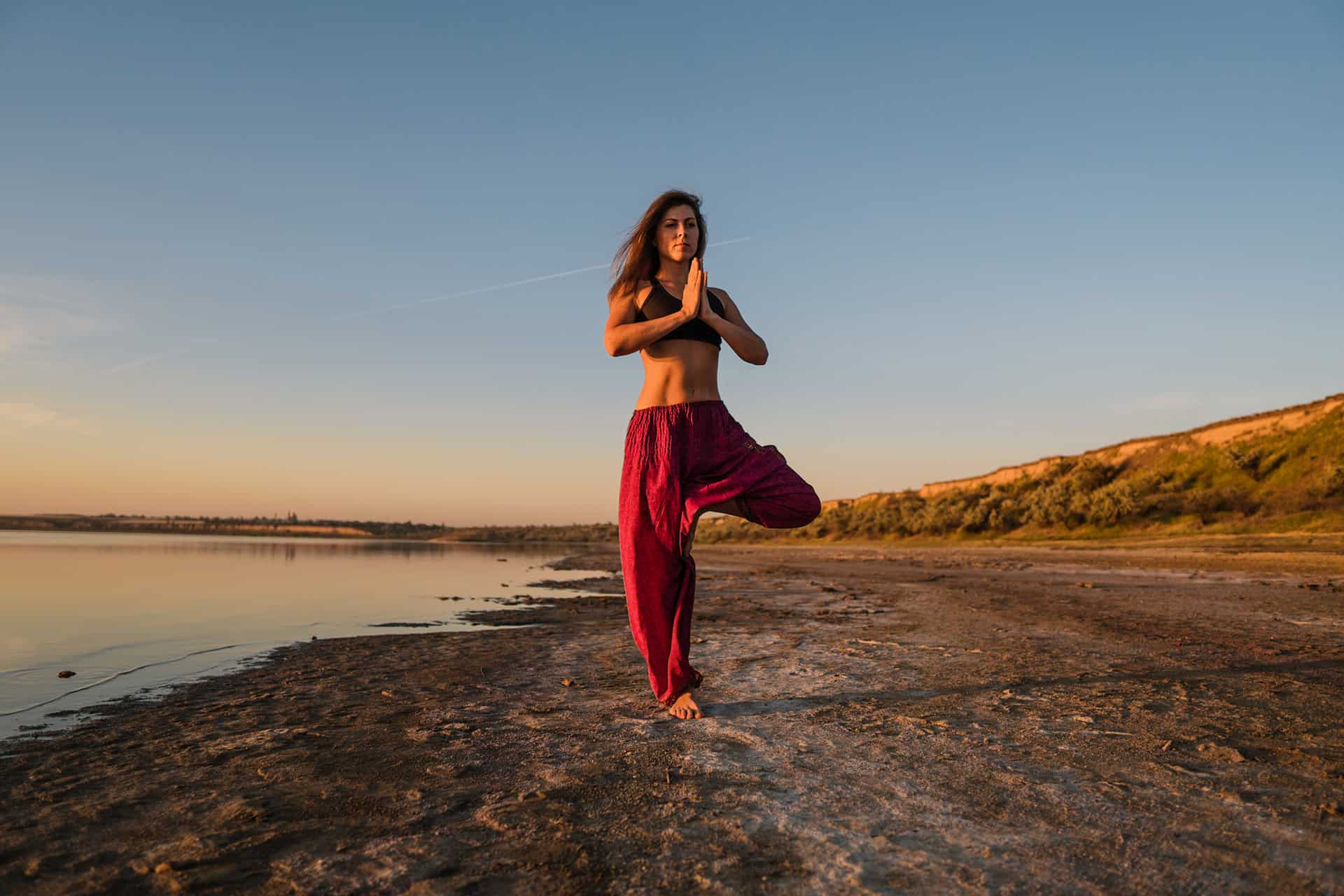 mujer meditando en la playa al atardecer